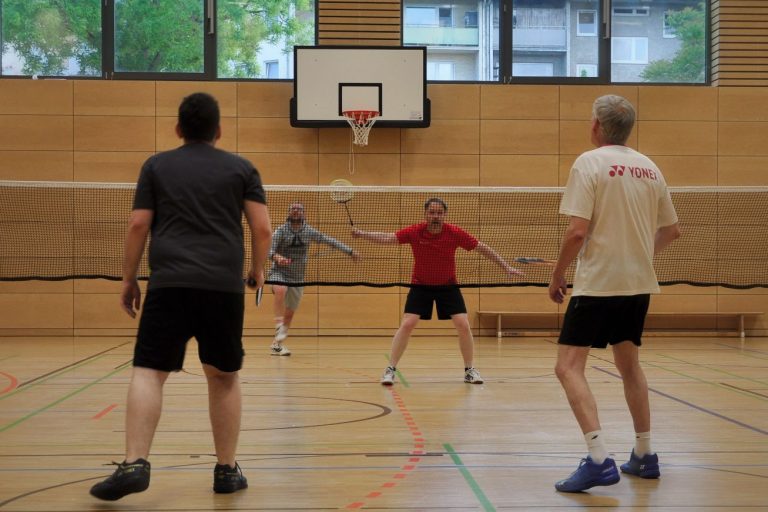 Vier Spieler mit Badmintonschlägern Vier Spieler mit Badmintonschlägern in einer Sporthalle spielen gegeneinander Badminton.